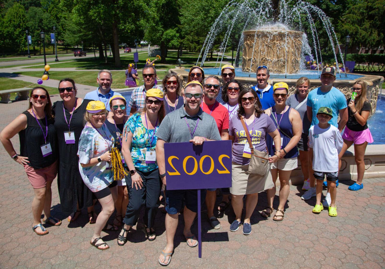 Members of the Class of 2022 pose with a 2002 sign during the alumni reunion parade